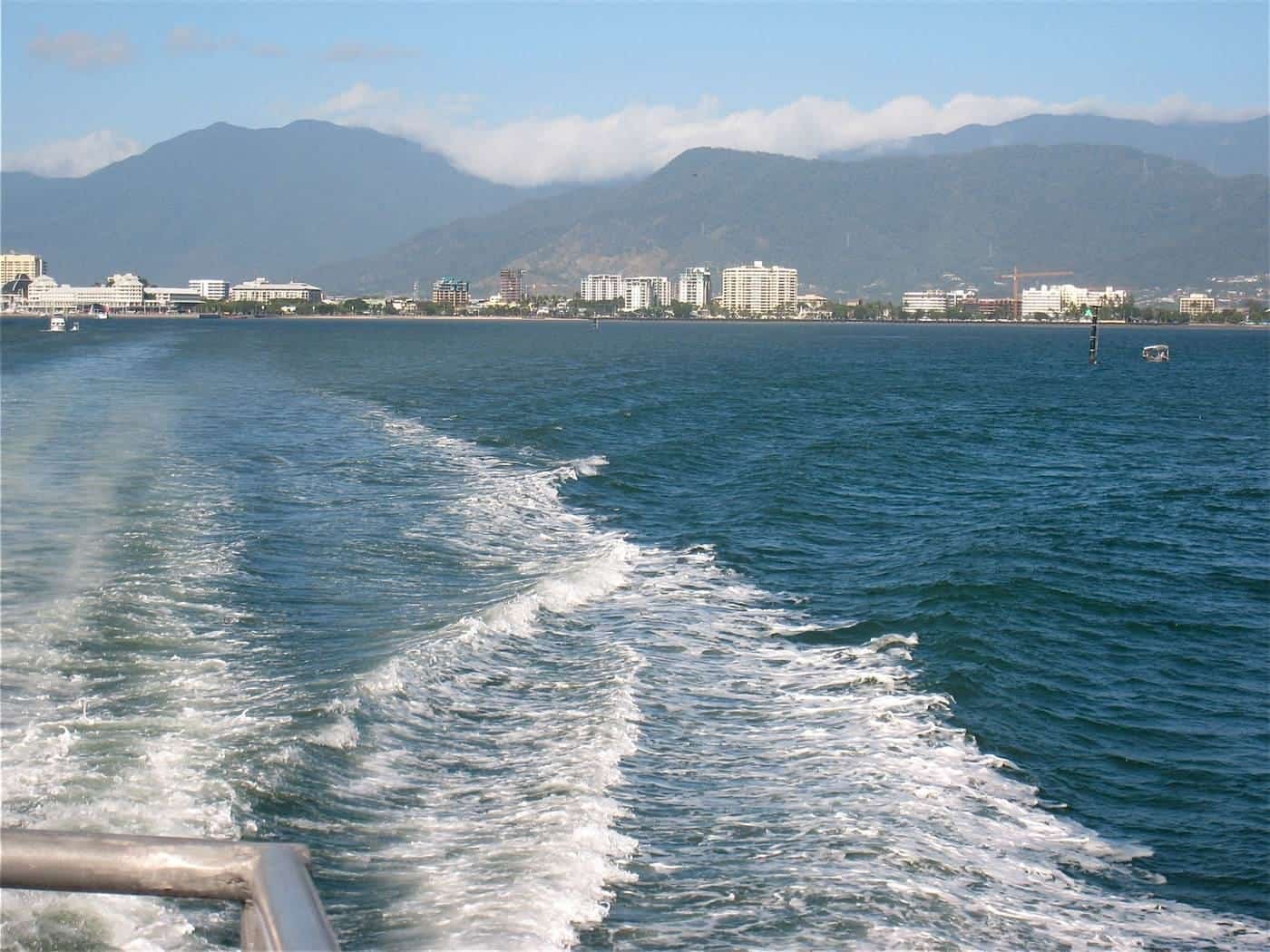 A tour boat leaving a white wake across blue water on the way to the reef