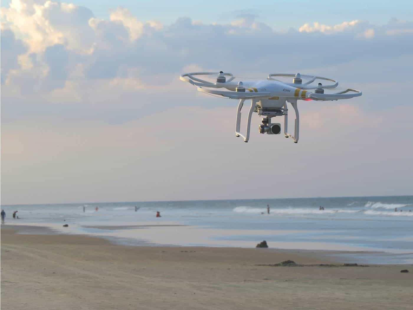 A small drone hovering above a sandy beach