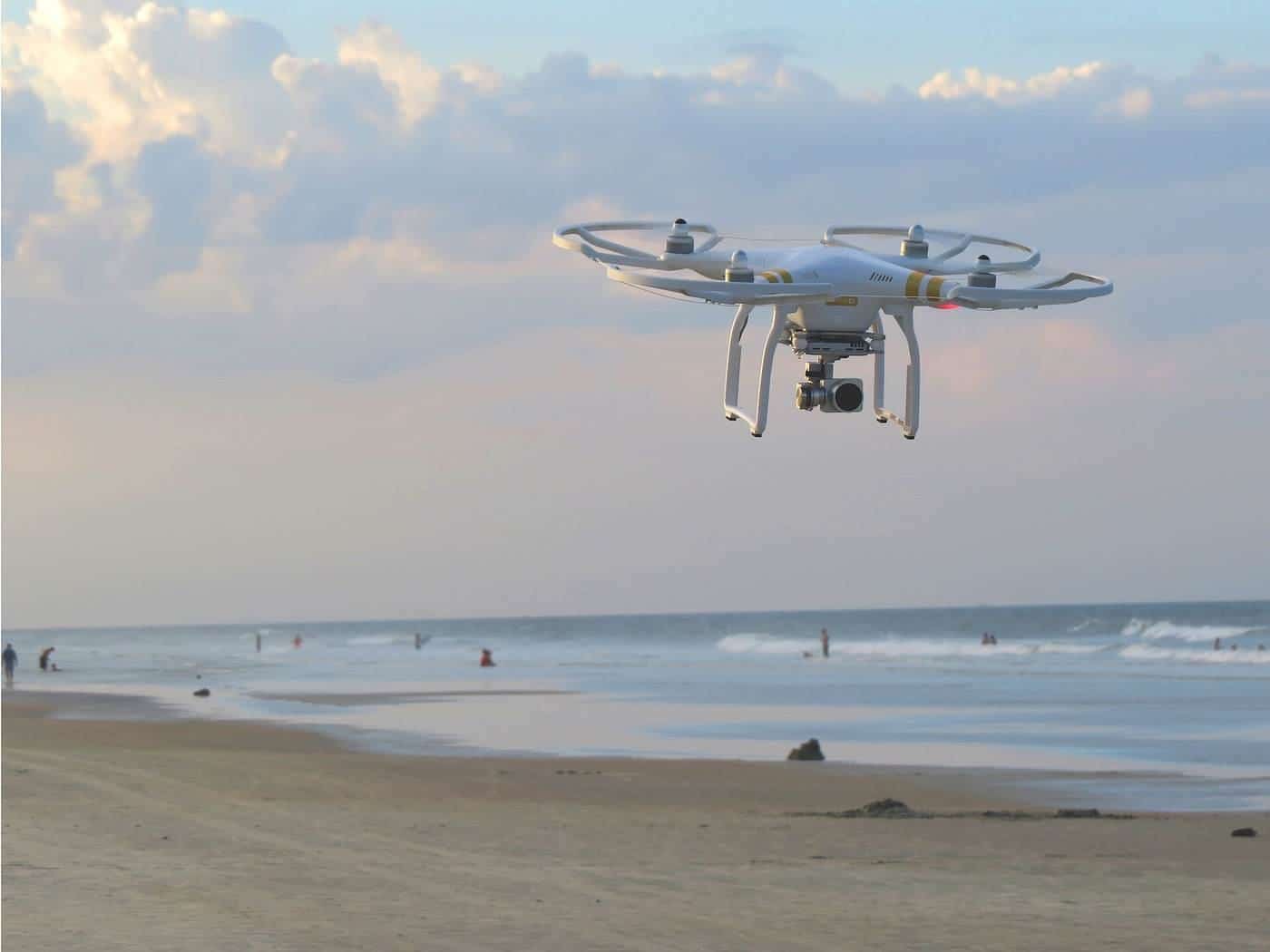 A small drone hovering above a sandy beach